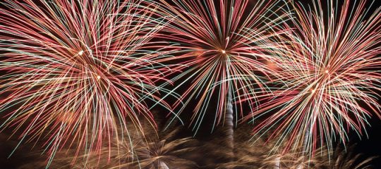 Photo d'un feu d'artifice automatique tiré au dessus d'une ville avec trois grosses explosions